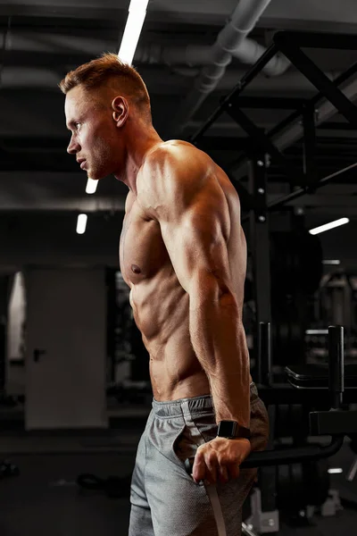 Retrato de cerca de un entrenamiento de hombre musculoso con barra de pesas en el gimnasio. Brutal culturista atlético hombre con seis pack, abdominales perfectos, hombros, bíceps, tríceps y pecho —  Fotos de Stock