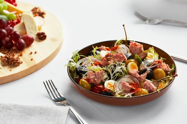 Fischsalat auf hellem Hintergrund, klassischer Nicoise mit großen Thunfischfiletstücken, Eiern, Oliven und Zwiebeln — Stockfoto