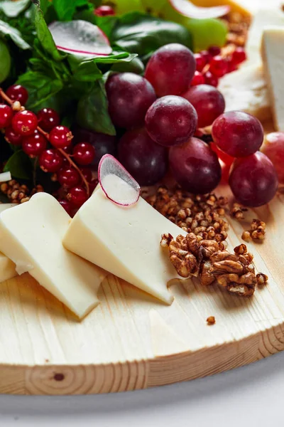 Different varieties of cheese with walnuts and grapes. — Stock Photo, Image
