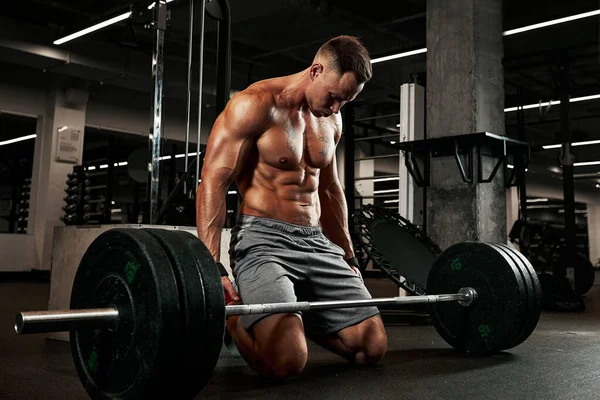 Desporto, fitness, levantamento de peso, lesões desportivas e conceito de pessoas - jovem e personal trainer com músculos de flexão de barra no ginásio — Fotografia de Stock