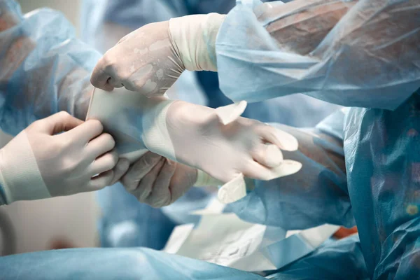 Nurses helping the surgeon to put on a glove in the operating room, many doctors hands in gloves. Washing gloves, part of the equipment of surgeons. — Φωτογραφία Αρχείου