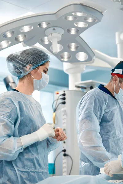 Femme chirurgien gros plan, à la table de la salle d'opération avec une équipe de collègues se préparant pour l'opération Sauver des vies, chirurgie moderne — Photo