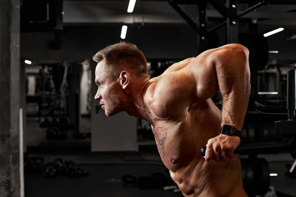Sportif agresifliği olan bir adam spor salonundaki düzensiz parmaklıklara baskı yapıyor, göğüs kasları ve trisepsleri çalıştırıyor. — Stok fotoğraf