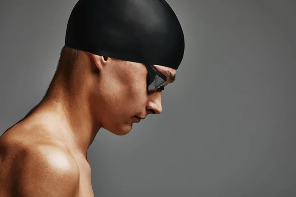 Twarz mężczyzny zbliżenie pływaka, szare tło, przestrzeń do kopiowania, młody facet pływak w masce i czapce — Zdjęcie stockowe