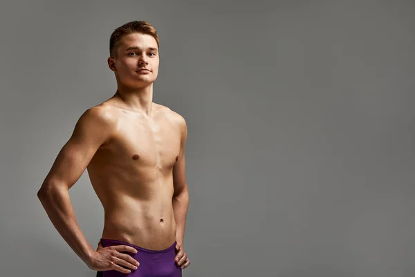 Jonge atleet zwemmer in uitstekende fysieke vorm kijkt naar de camera, halve lengte portret op een grijze achtergrond, kopieerruimte, motivatie voor sport, reclame banner. — Stockfoto