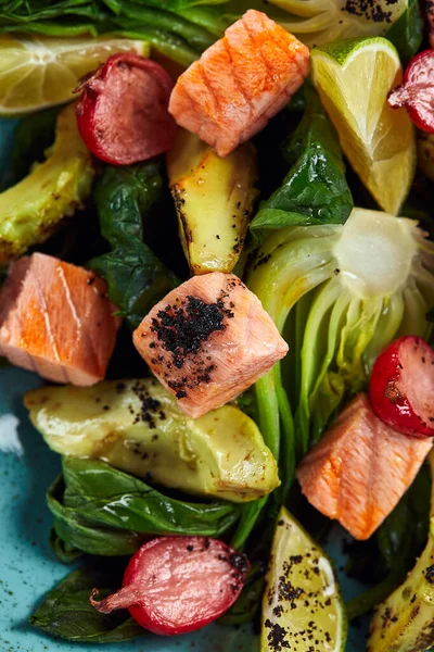 Nahaufnahme von Lachswürfeln mit Gemüse, gedünstetem Gemüse, gegrillter Avocado, als heiße Fischvorspeise, gegrilltem Lachs mit Gemüsemischung — Stockfoto