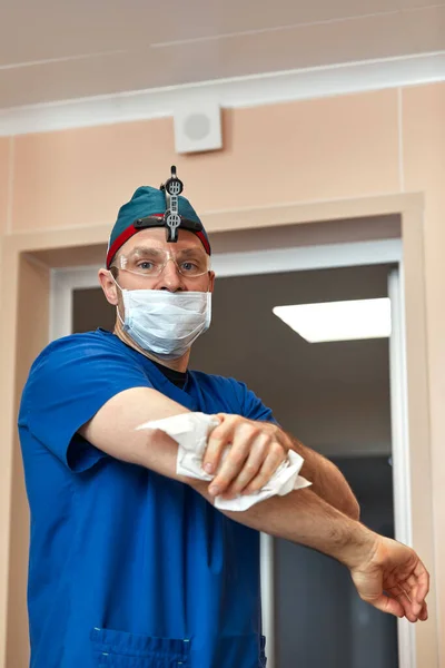 The male surgeon washes his hands before the operation, preparing for the operation, disinfecting the hands before the treatment.