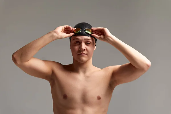 Retrato de um nadador em boné e máscara, retrato de meia-distância, jovem atleta nadador usando um boné e máscara para nadar, cópias do espaço, fundo cinza — Fotografia de Stock