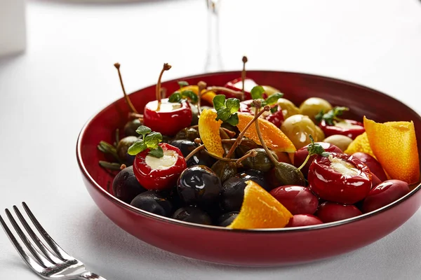 Verduras conservadas em escabeche em uma chapa, azeitonas, azeitonas pretas, pimentas recheadas, rabanetes. Legumes variados, legumes com especiarias em close-up de óleo — Fotografia de Stock