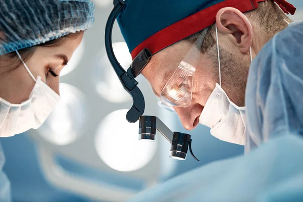 외과 의사들은 수술중이고, 수술중에는 남녀 의사들로 이루어진 팀 이 있으며, 의사들은 수술실에 묶여 있다. — 스톡 사진