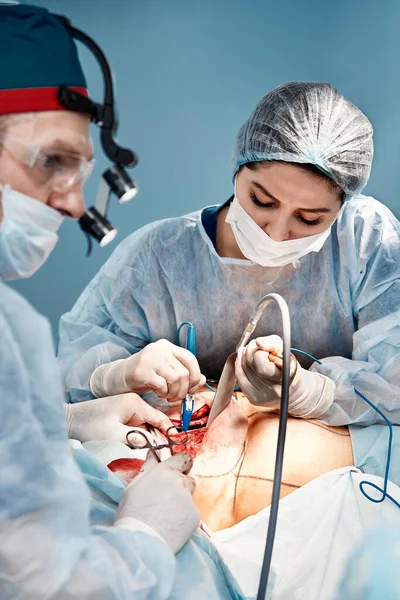 Artsen voeren borstchirurgie na verwijdering van een kankergezwel, bestrijding van vrouwelijke borstkanker, mammoplastiek concept. — Stockfoto