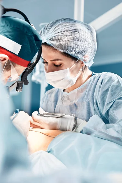 외과 의사들은 수술중이고, 수술중에는 남녀 의사들로 이루어진 팀 이 있으며, 의사들은 수술실에 묶여 있다. — 스톡 사진
