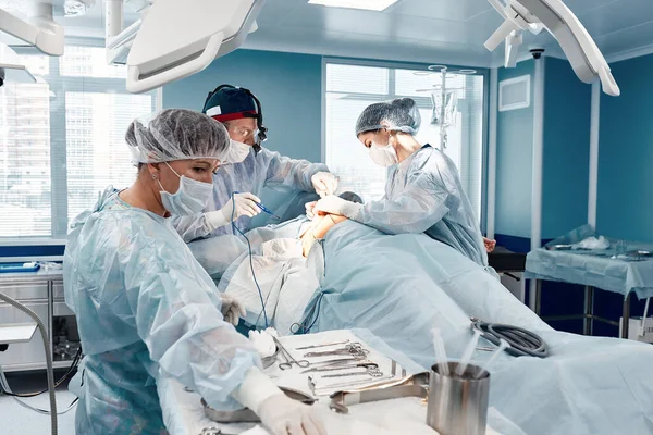 The surgical team operates on the patient in the operating room. A well-trained anesthesiologist with sophisticated apparatus accompanies the patient throughout the entire operation. — Stock fotografie