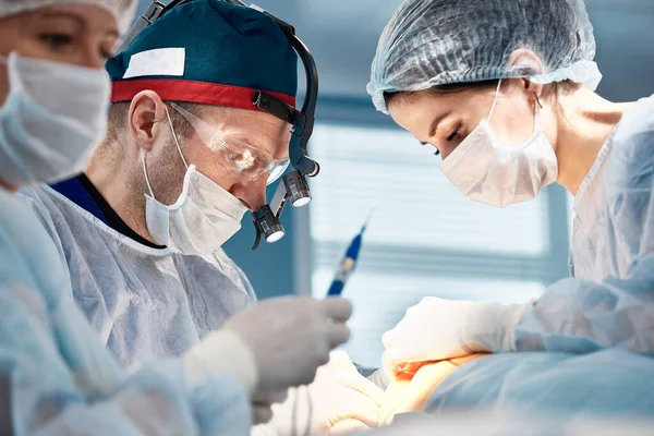 The surgical team operates on the patient in the operating room. A well-trained anesthesiologist with sophisticated apparatus accompanies the patient throughout the entire operation. — Foto de Stock