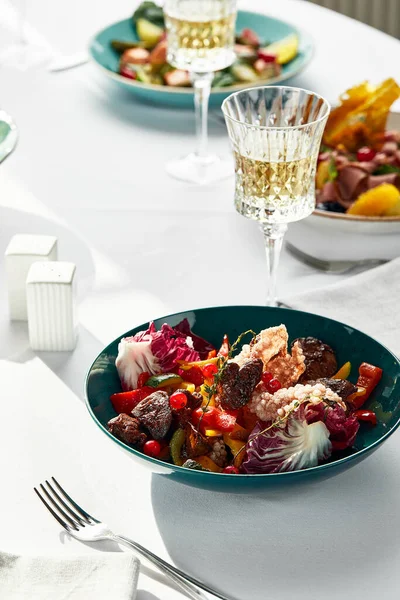 Ein Salat aus Leber, Gemüse und Beeren, auf einem festlichen Tisch mit Blumen, Wein und anderen Snacks, gebratene Kalbsleber in einem Salat. — Stockfoto
