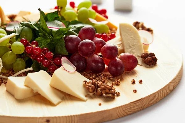 Different varieties of cheese with walnuts and grapes. — Stock Photo, Image