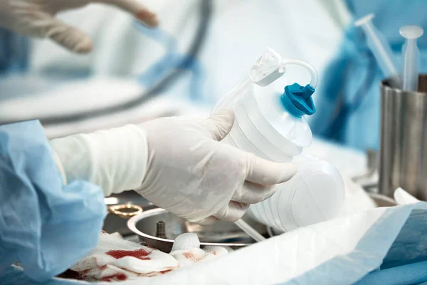 The surgeons hands are installing an expander for the correction of the mammary gland after the removal of a cancerous tumor, a close-up of the doctors hands with gloves preparing for the — Stock Photo, Image