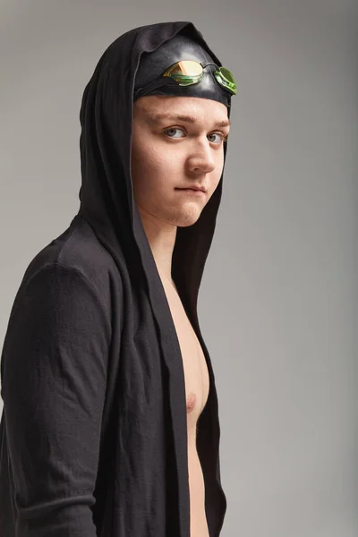 Guy swimmer in a cap, mask and bathrobe for swimming, on a gray background, preparing for the swim — Stock Photo, Image