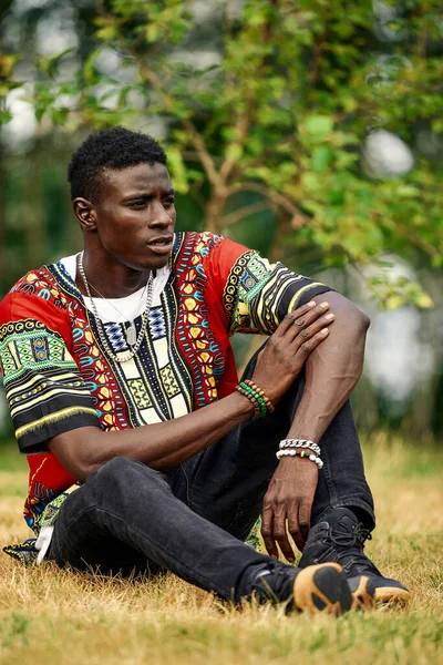 An African man in South African national clothes, a black young man resting in a park in national clothes. — Stock Photo, Image