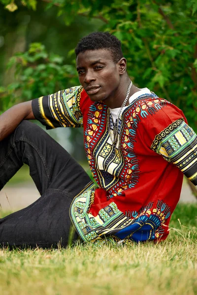 An African man in South African national clothes, a black young man resting in a park in national clothes.