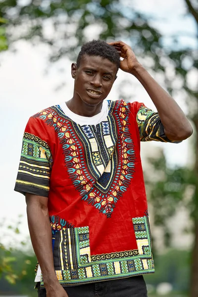 Un hombre africano con ropa nacional sudafricana, un joven negro descansando en un parque con ropa nacional. — Foto de Stock