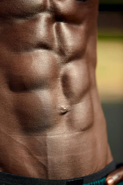 Male muscular belly, close-up, black mans abdominal relief.