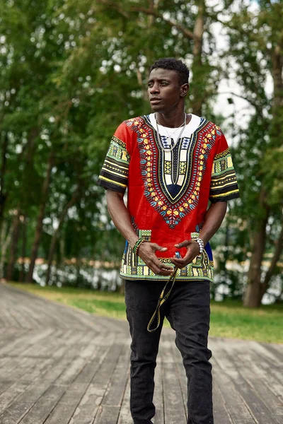 Un hombre africano con ropa nacional sudafricana, un joven negro descansando en un parque con ropa nacional. — Foto de Stock