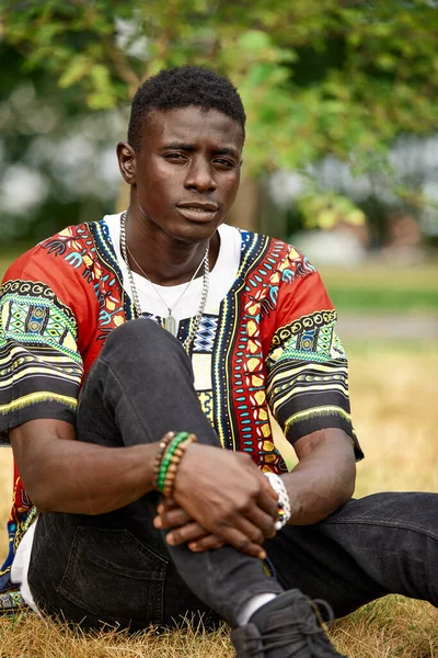 An African man in South African national clothes, a black young man resting in a park in national clothes.