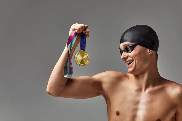 一名身强体壮的运动员手持一枚奖牌、一个胜利的理念、一个灰色的背景、一个复制的空间庆祝胜利 — 图库照片