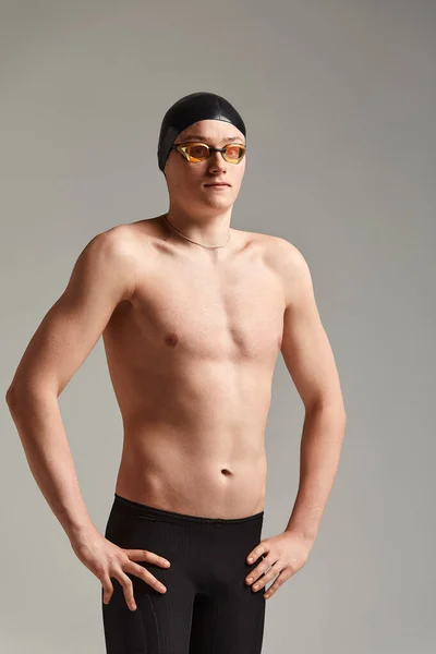 Jovem nadador do sexo masculino se preparando para o início, close-up retrato de um nadador em uma máscara e um chapéu, fundo cinza, espaço de cópia, conceito de natação. — Fotografia de Stock