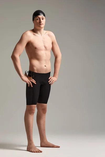 Um homem nadador em óculos para nadar em pleno crescimento em um fundo cinza, preparando um atleta para um mergulho, espaço de cópia — Fotografia de Stock
