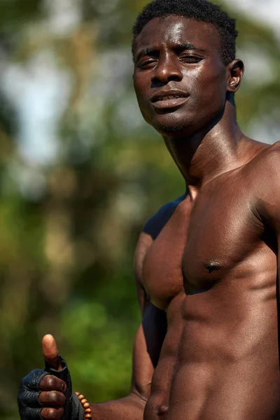 Deportista negro muestra un maniquí durante el entrenamiento, ejercicio al aire libre, afroamericanos entrenan en el campo de deportes, en un entorno urbano, primer plano, espacio de copia. — Foto de Stock