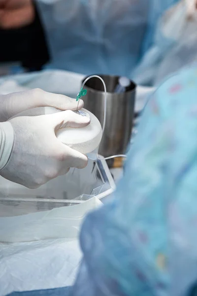 Chirurgové během operace s prsními implantáty v rukou, instalace prsních implantátů, chirurgie. Plastická chirurgie, korekce prsou, mammoplastika. — Stock fotografie