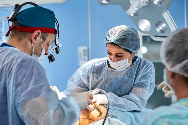 Ameliyat sırasında cerrah grubunu gösteren gerçek ameliyathane ortamında estetik yağ aldırma ameliyatı — Stok fotoğraf