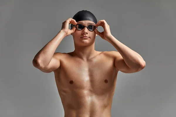 Νεαρός κολυμβητής προετοιμάζεται για την εκκίνηση, κοντινό πορτραίτο κολυμβητή με μάσκα και καπέλο, γκρι φόντο, αντιγραφή χώρου, ιδέα κολύμβησης. — Φωτογραφία Αρχείου