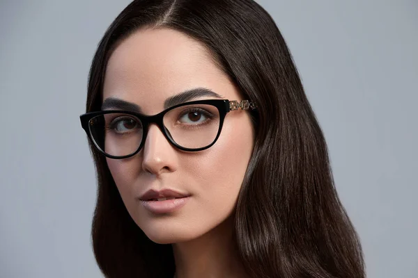 Porträtt av en vacker brunett kvinna i glasögon närbild, attraktiv kvinna i snygga glasögon på en grå bakgrund med frisk vacker färg hud, grå bakgrund, kopiera utrymme — Stockfoto