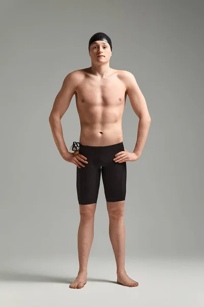 Portrait of a swimmer in a cap and mask, half-length portrait, young athlete swimmer wearing a cap and mask for swimming, copies of space, gray background