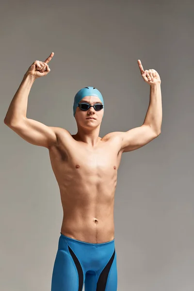 Jovem nadador profissional indica com os dedos para cima mostrando um espaço em branco. — Fotografia de Stock