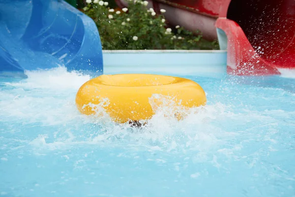 一个8岁的男孩骑在水上公园的充气圆圈上，用飞溅的滑水让他高兴 — 图库照片