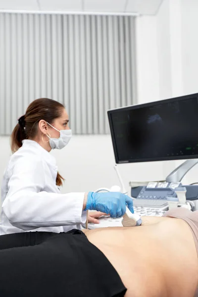Женщина-врач делает пациентке УЗИ брюшной полости. Ультразвуковой сканер в руках врача. — стоковое фото