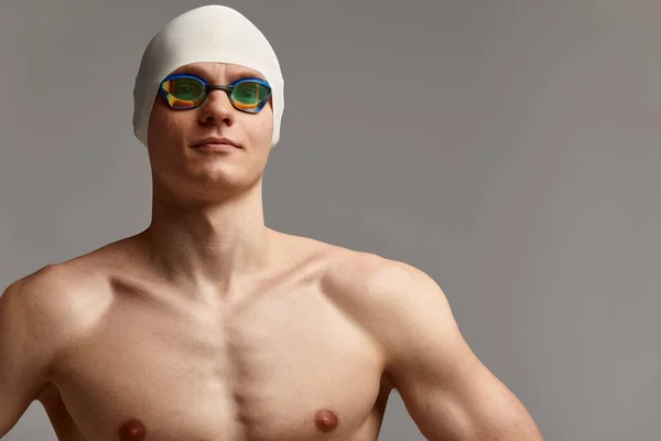 Retrato de un nadador con gorra y máscara, retrato de medio cuerpo, joven nadador atleta con gorra y máscara para nadar, copias del espacio, fondo gris — Foto de Stock