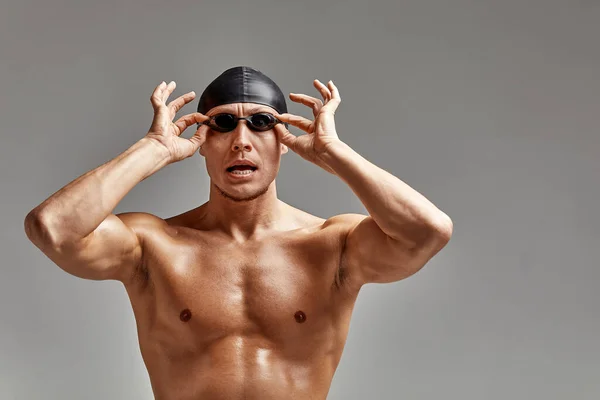 Retrato de um nadador em boné e máscara, retrato de meia-distância, jovem atleta nadador usando um boné e máscara para nadar, cópias do espaço, fundo cinza — Fotografia de Stock