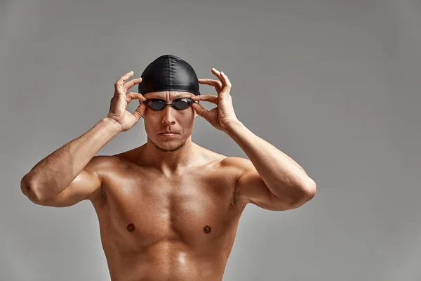 Портрет плавця в шапці і масці, портрет напівдовжини, молодий спортсмен плаває в шапці і масці для плавання, копії простору, сірий фон — стокове фото