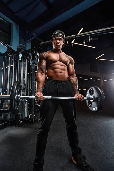 Güçlü ve kaslı Afro-Amerikan adam spor salonunda modern ekipmanlarla antrenman yapıyor. Kaslı şişirilmiş fitness eğitmeninin portresi — Stok fotoğraf