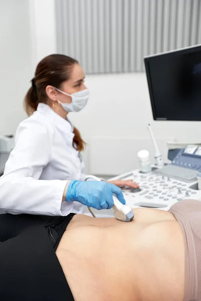 Médica feminina dá ao paciente um ultra-som abdominal feminino. Scanner de ultra-som nas mãos de um médico. — Fotografia de Stock