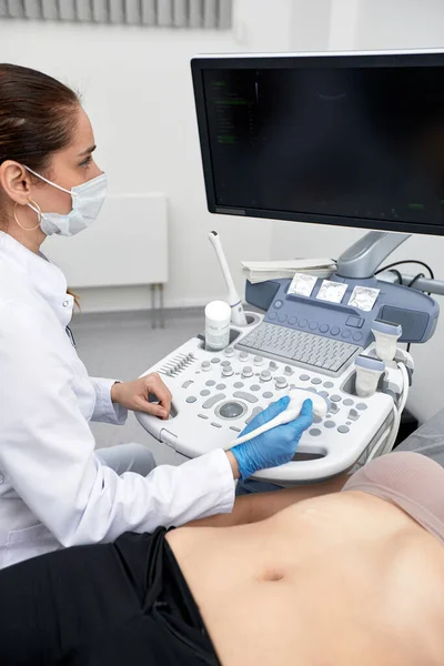 Médica feminina dá ao paciente um ultra-som abdominal feminino. Scanner de ultra-som nas mãos de um médico. — Fotografia de Stock