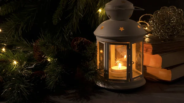Yanan mumlu beyaz fener. Nooks, noel ağacı dalı ve arka planda ışıklar. Gece karanlığı resmi. Noel gizemi havası.