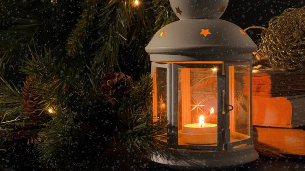Yanan mumlu beyaz fener. Kitaplar, Noel ağacı dalı ve arka planda ışıklar. Kar yağıyor. Gece karanlığı resmi. Noel gizemi havası.