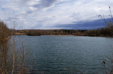 Fırtınalı hava. Göletin altındaki bulutlu gökyüzü. Ufukta kuru ot ve orman görünüyor. Doğa arkaplanı.