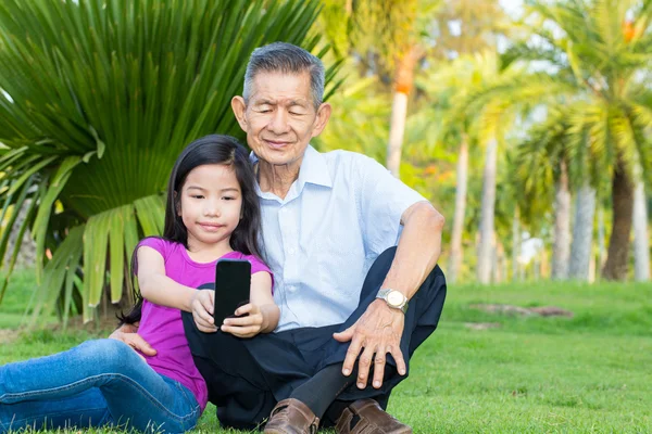 Abuelo asiático y nieto tomando selfie con smartphone en el parque — Foto de Stock